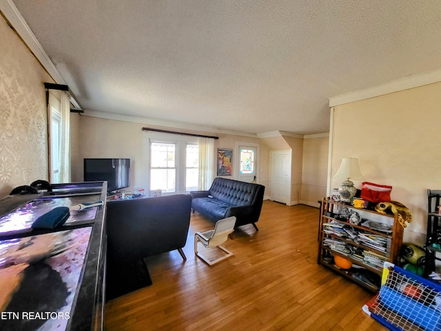 living room with a textured ceiling, ornamental molding, and hardwood / wood-style floors