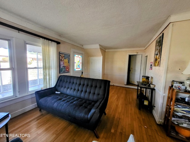 living area featuring ornamental molding, wood-type flooring, a textured ceiling, and baseboards