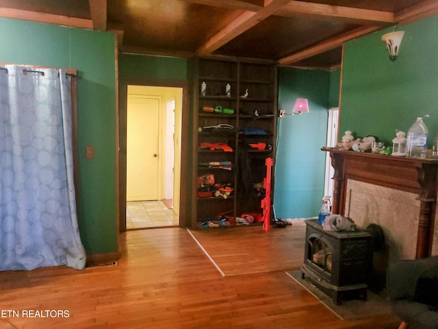 rec room with a wood stove and wood finished floors