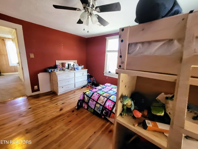 bedroom with ceiling fan, wood finished floors, and baseboards