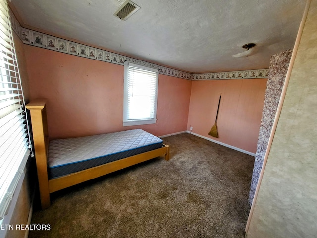 unfurnished bedroom featuring carpet floors, baseboards, visible vents, and a textured ceiling