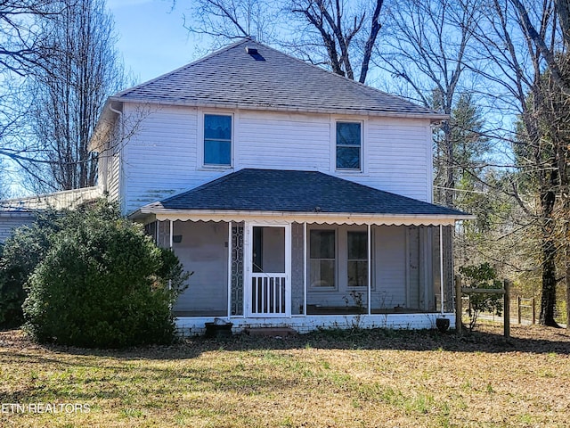 view of front of house featuring a front lawn, roof with shingles, and a sunroom