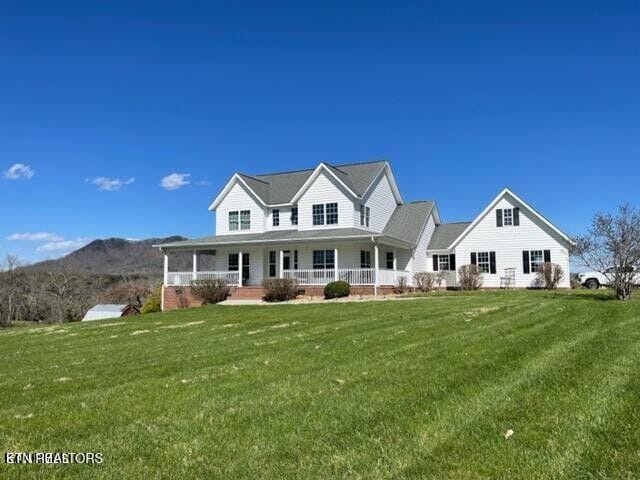 view of front of property with a porch, a mountain view, and a front lawn