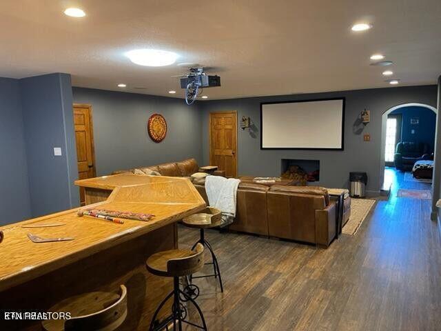 cinema room featuring dark wood-style floors, arched walkways, and recessed lighting