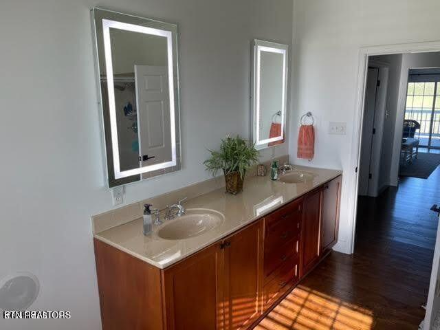 bathroom with double vanity, a sink, and wood finished floors