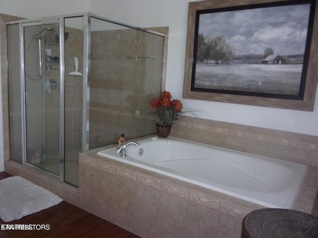 full bathroom featuring a stall shower, a bath, and wood finished floors