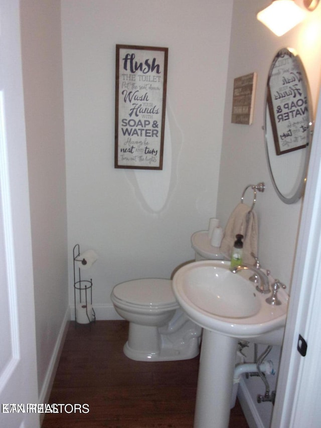 bathroom featuring toilet, baseboards, and wood finished floors