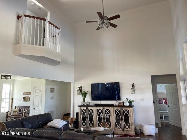 living area featuring a high ceiling, wood finished floors, and a ceiling fan