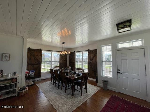 dining room with wood finished floors, wooden ceiling, baseboards, and a barn door