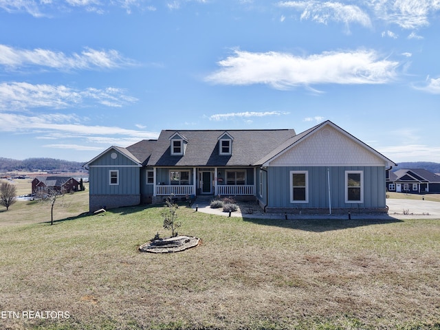 view of front facade featuring covered porch, a shingled roof, board and batten siding, and a front yard