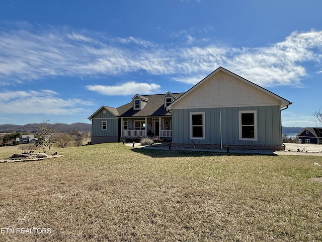 view of front facade with covered porch, board and batten siding, and a front yard