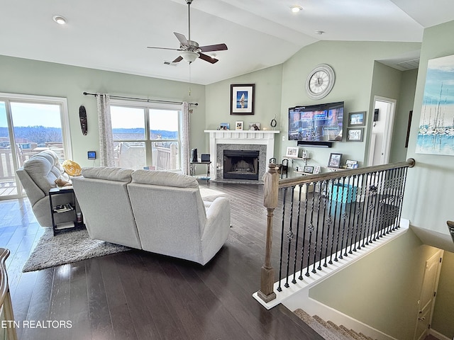 living area featuring vaulted ceiling, ceiling fan, dark wood-style flooring, and a fireplace