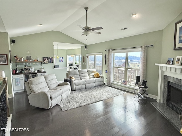 living room with a fireplace, visible vents, a ceiling fan, vaulted ceiling, and dark wood-style floors