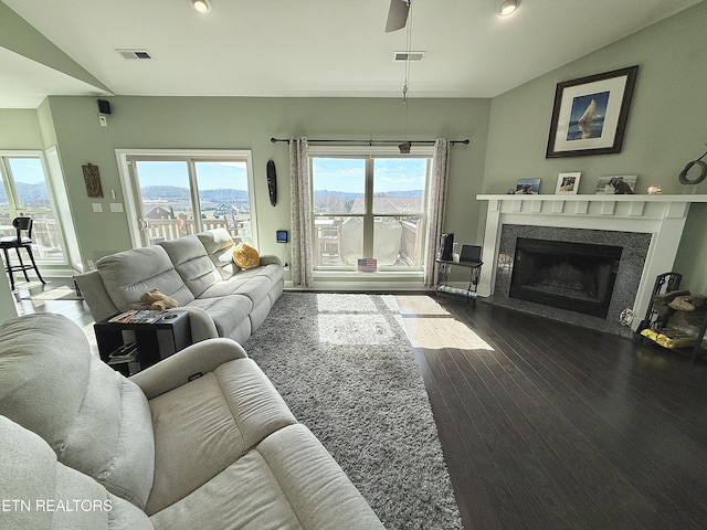 living area featuring lofted ceiling, a fireplace, dark wood-style floors, and visible vents