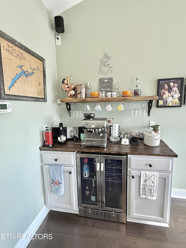 bar featuring a bar, wine cooler, baseboards, and dark wood-style flooring