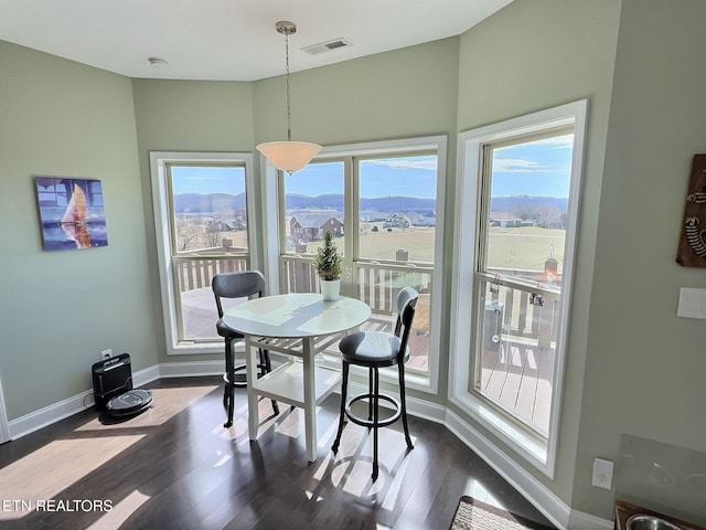 dining space featuring baseboards, visible vents, and dark wood finished floors