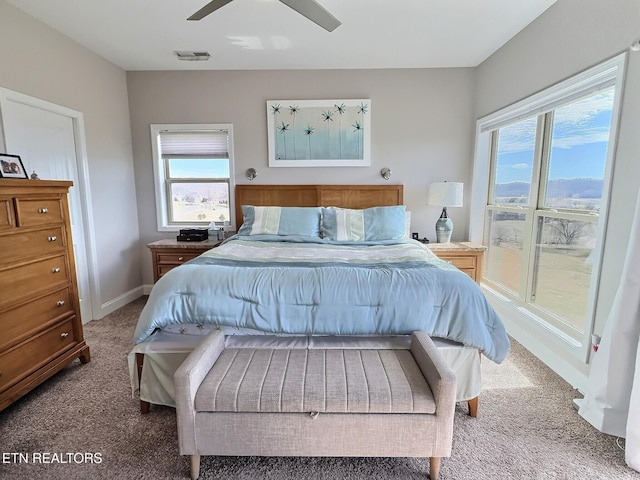 carpeted bedroom featuring ceiling fan, multiple windows, visible vents, and baseboards