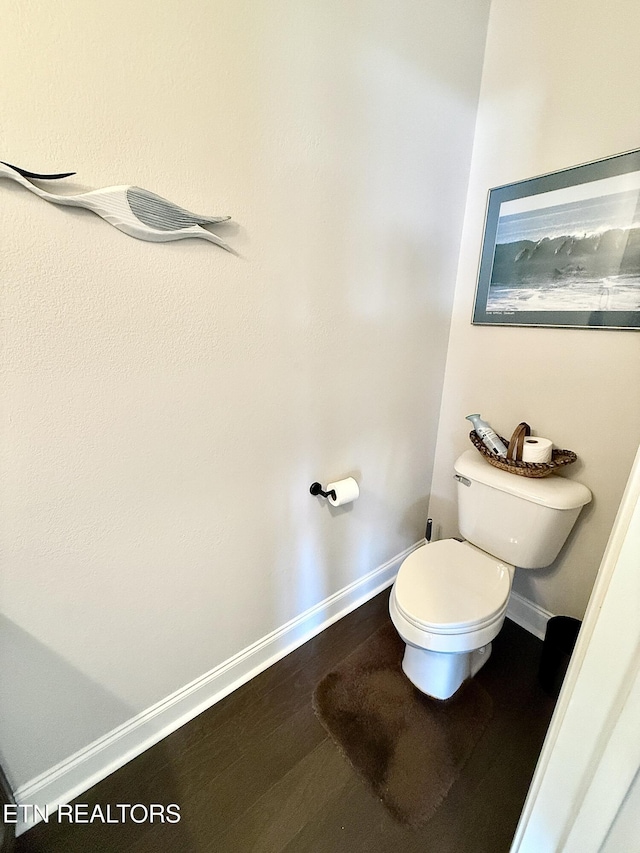 bathroom with toilet, baseboards, and wood finished floors