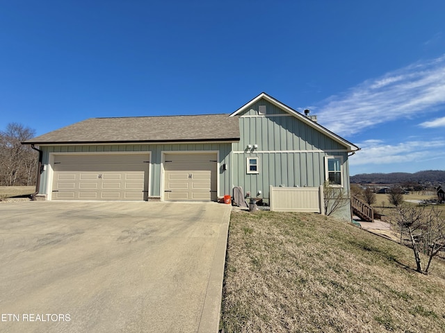 view of front of home featuring a garage, concrete driveway, a shingled roof, and board and batten siding