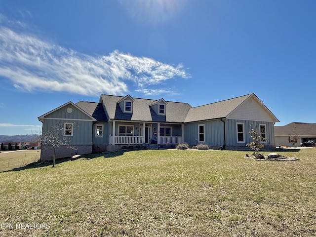 view of front facade with covered porch, a front lawn, board and batten siding, and roof with shingles