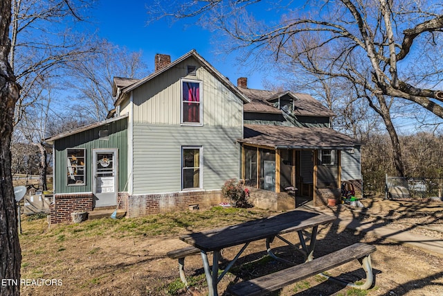 rear view of property with a sunroom, brick siding, and a chimney