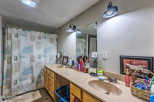 full bathroom featuring wood finished floors, a sink, and double vanity