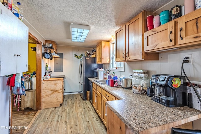 kitchen featuring light wood-style floors, a textured ceiling, stainless steel microwave, and a sink