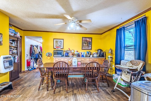 dining area featuring a textured ceiling, a ceiling fan, crown molding, and wood finished floors