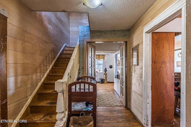 stairway featuring wood walls, a textured ceiling, and wood finished floors