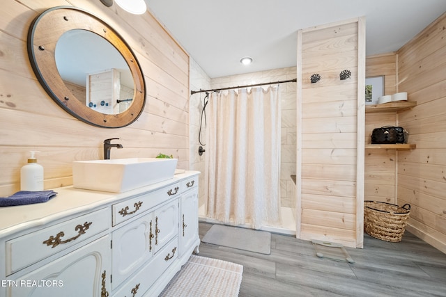 full bathroom featuring tiled shower, wooden walls, and vanity