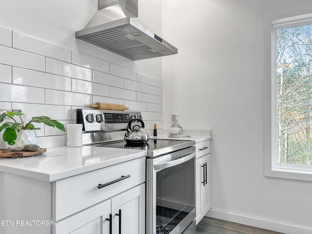 kitchen featuring stainless steel range with electric stovetop, a healthy amount of sunlight, wall chimney exhaust hood, and tasteful backsplash