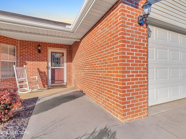 property entrance featuring brick siding and an attached garage