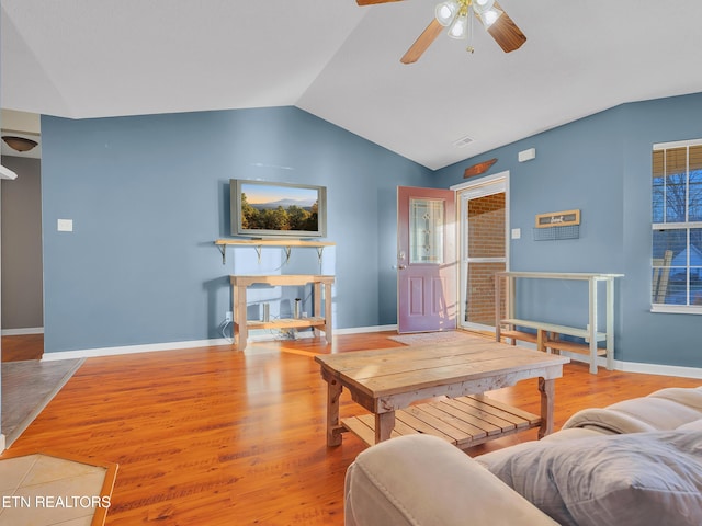 living area featuring baseboards, vaulted ceiling, and wood finished floors