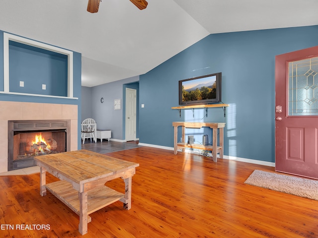 living area with vaulted ceiling, a fireplace, wood finished floors, and baseboards