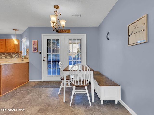 dining room with a chandelier, visible vents, and baseboards