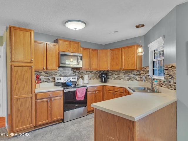 kitchen featuring tasteful backsplash, appliances with stainless steel finishes, light countertops, pendant lighting, and a sink