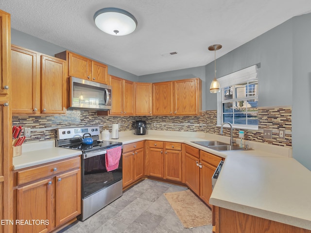 kitchen with stainless steel appliances, light countertops, visible vents, hanging light fixtures, and a sink