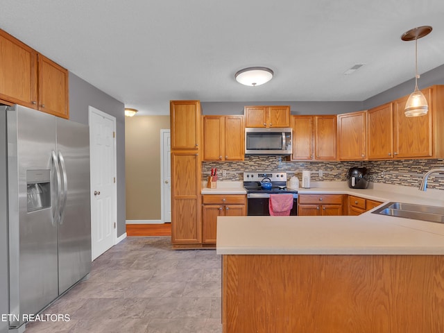 kitchen featuring appliances with stainless steel finishes, light countertops, a sink, and decorative backsplash