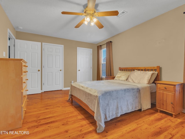 bedroom featuring visible vents, ceiling fan, light wood-style flooring, and baseboards