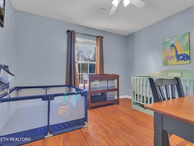 bedroom featuring baseboards, visible vents, ceiling fan, wood finished floors, and a textured ceiling