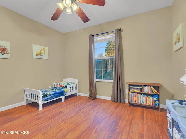 bedroom featuring ceiling fan, baseboards, and wood finished floors