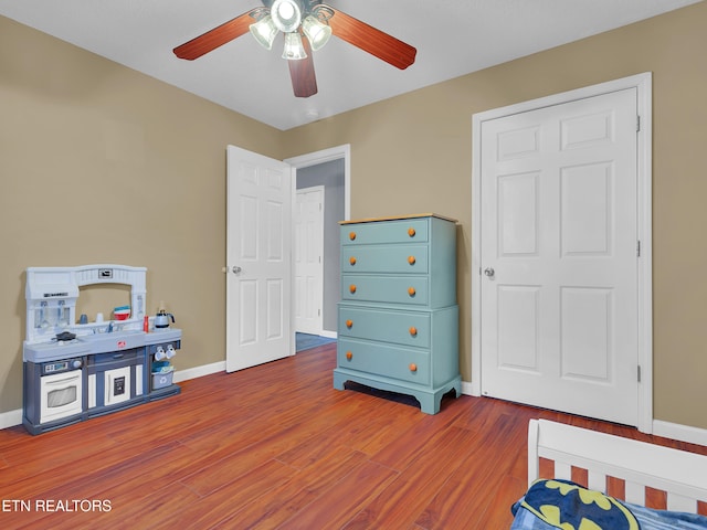 bedroom featuring wood finished floors, a ceiling fan, and baseboards