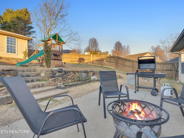 view of patio / terrace with an outdoor fire pit, a playground, and a fenced backyard