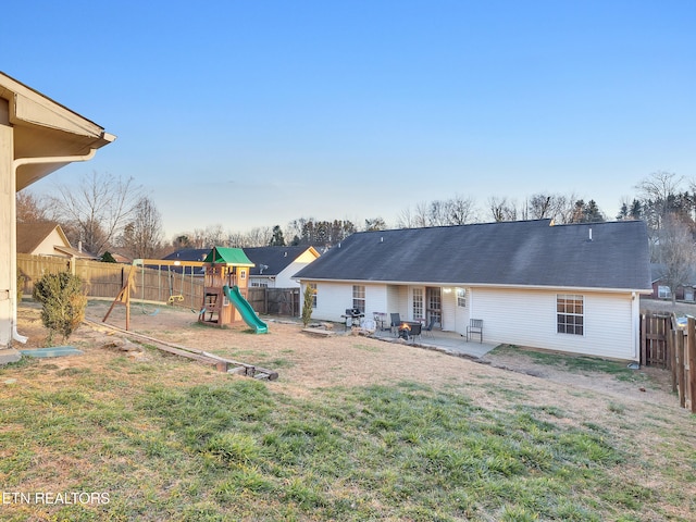 rear view of house with a patio area, a fenced backyard, a lawn, and a playground