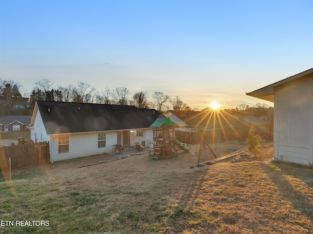 back of property featuring a playground, fence, a patio, and a lawn