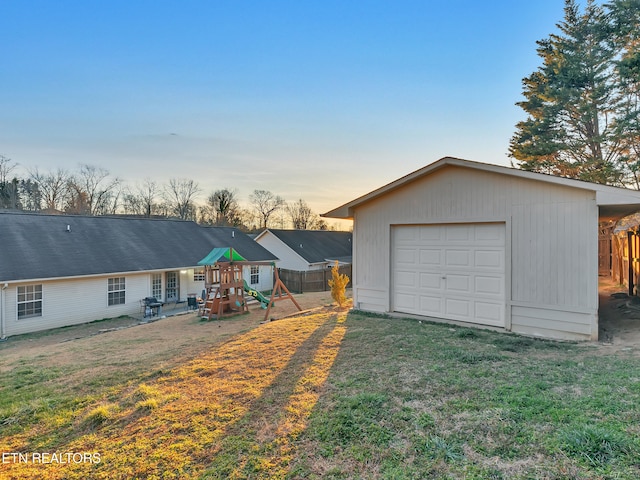 back of property with driveway, fence, a playground, and an outbuilding