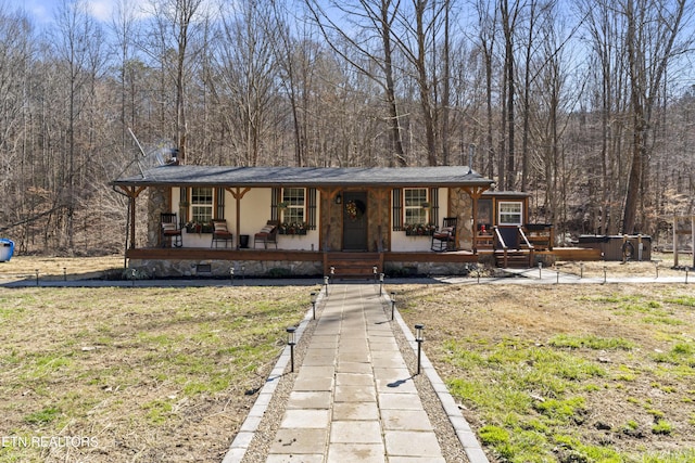 view of front of property featuring a front lawn, a porch, and a wooded view