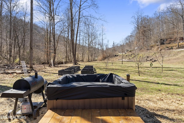 view of yard with a hot tub and a view of trees