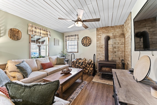 living room with a wood stove, ceiling fan, wood ceiling, and dark wood finished floors