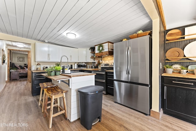 kitchen with open shelves, stainless steel appliances, light wood-style floors, white cabinetry, and a kitchen island